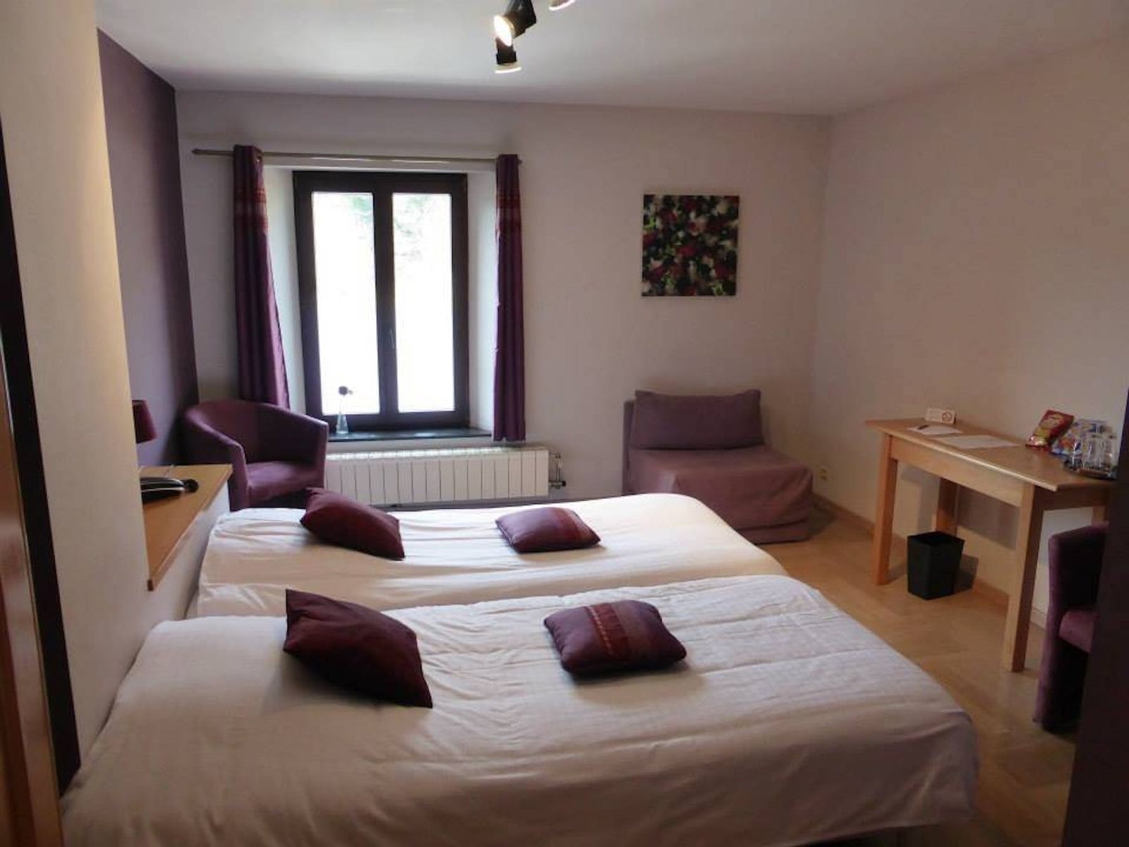 Chambre lumineuse avec deux lits et un coin salon